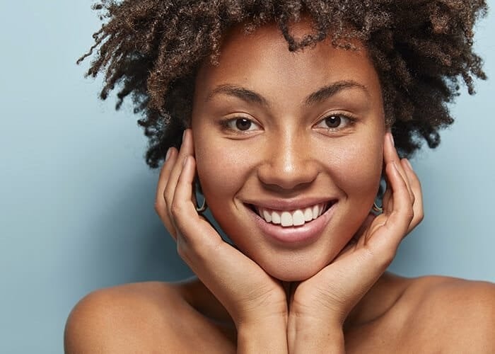 Smiling person with curly hair against blue background.
